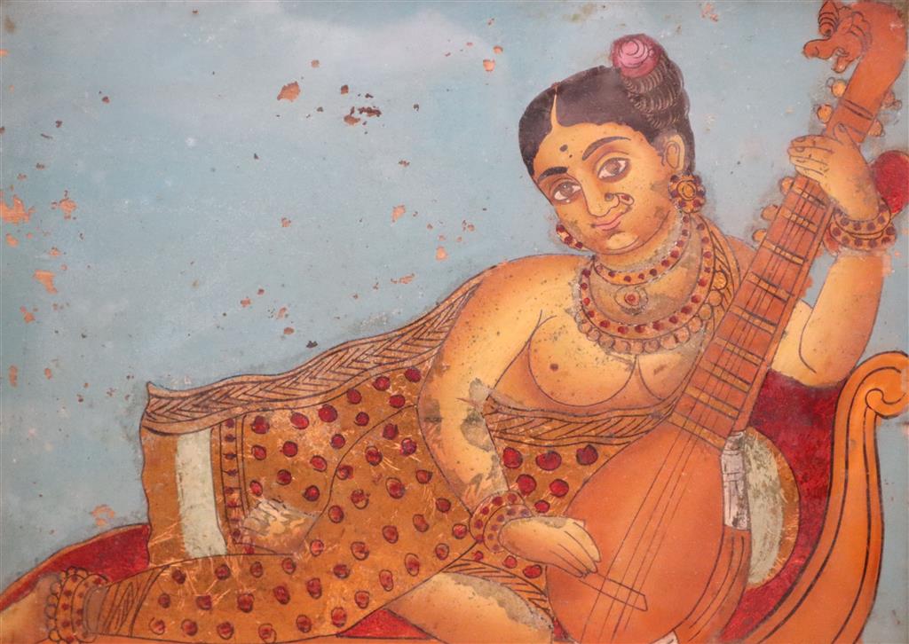 19th century Indian School, reverse painted and gilt glass, Woman playing a sitar, 25 x 30cm